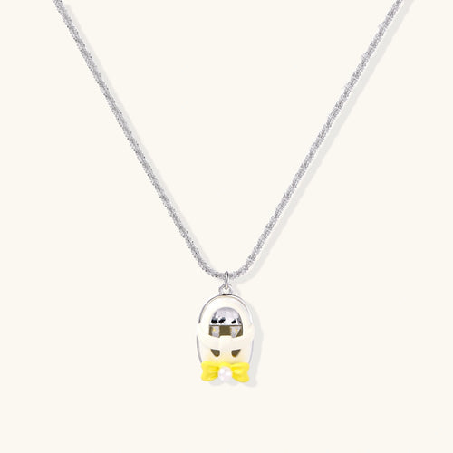 Chrome egg-shaped pendant with kawaii face, yellow bow, and pearl detail on silver chain against white background